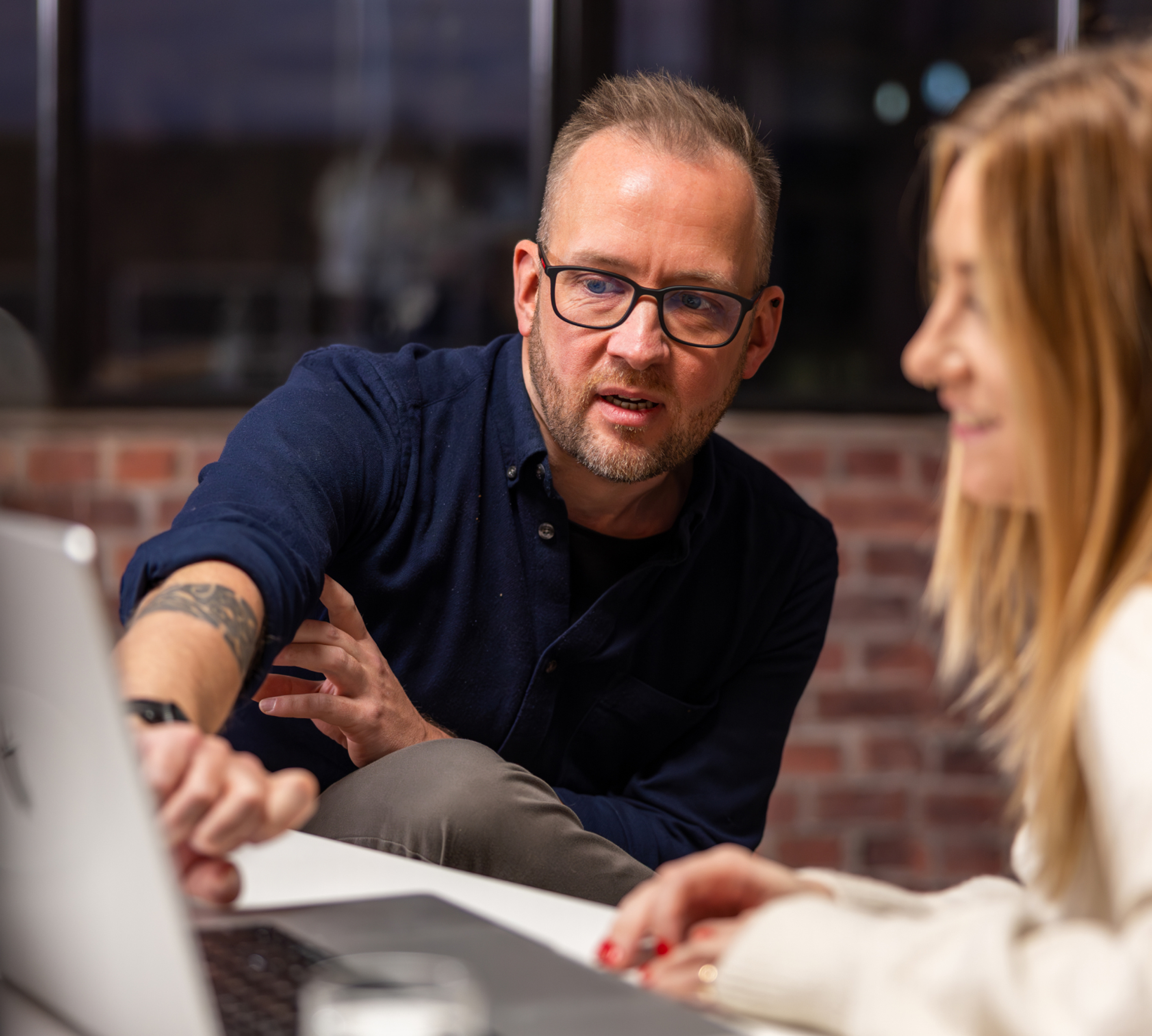 a person and person sitting at a table looking at a laptop