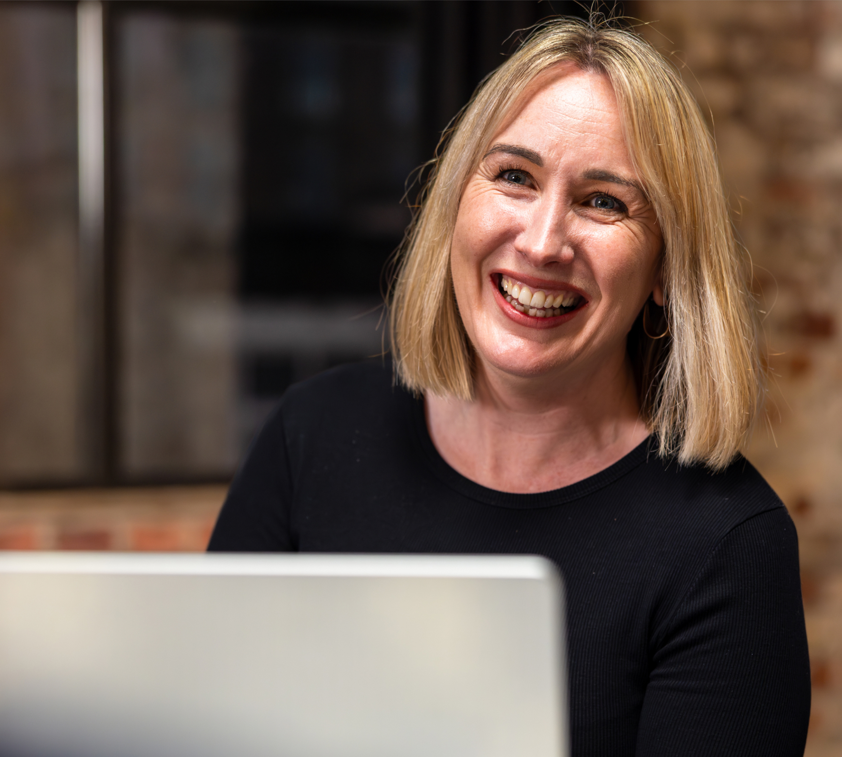 a person smiling at a laptop