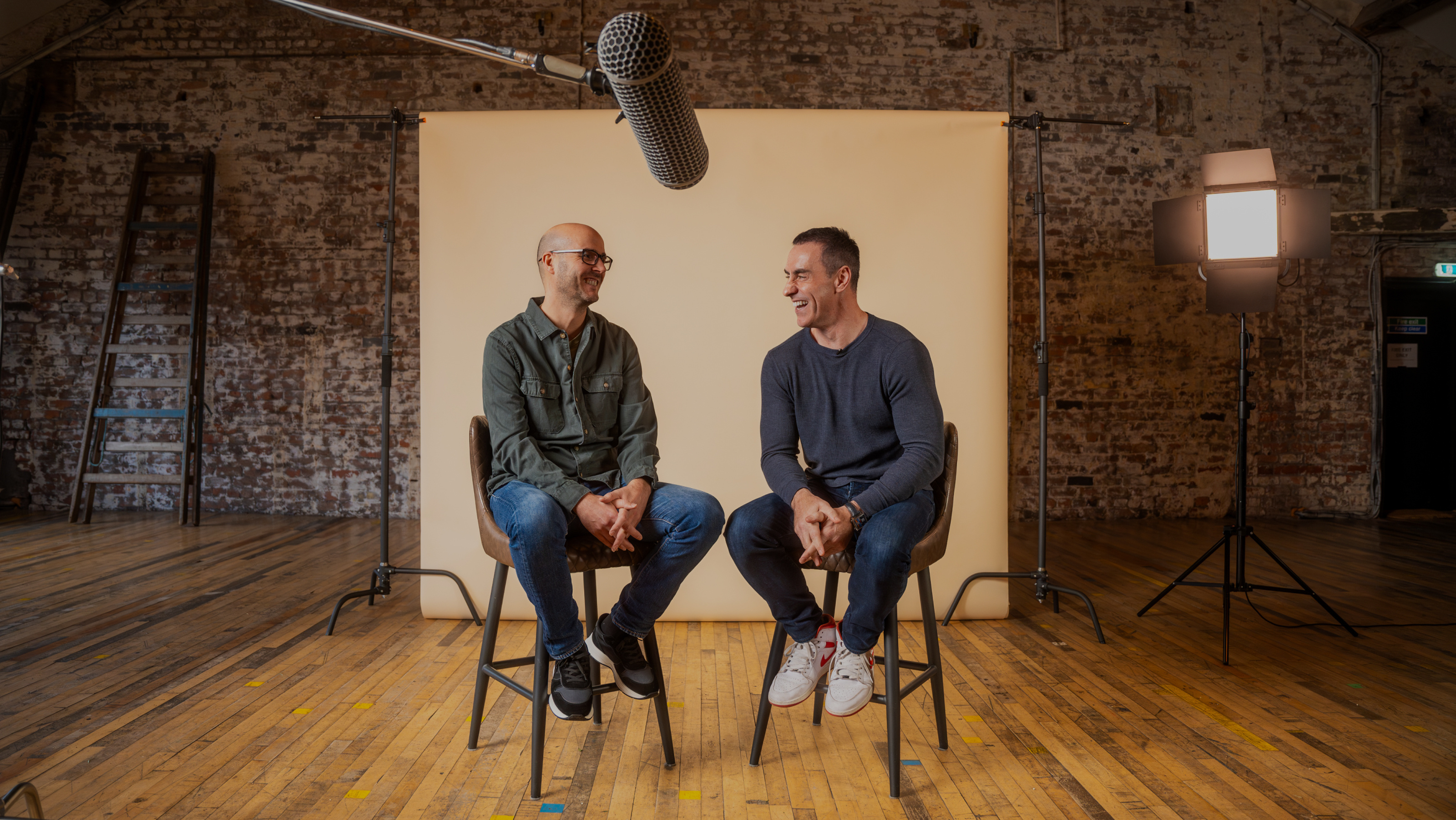 two men sitting in chairs in front of a microphone
