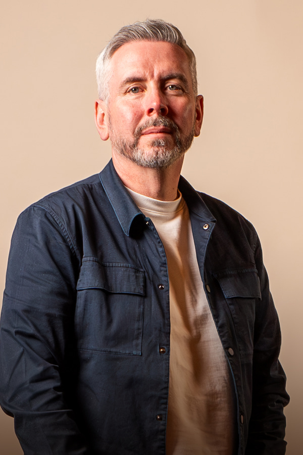 a person with grey hair and beard wearing a blue jacket
